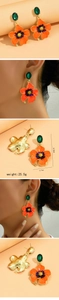 Detail view of sunflower earrings with orange enamel, green gems, and size 5.8x3.7cm
