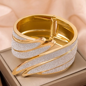 Elegant gold metal bangle with sparkling silver glitter feather design on pink silk