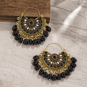 Bohemian fan-shaped tassel earrings in gold and black enamel on wooden background