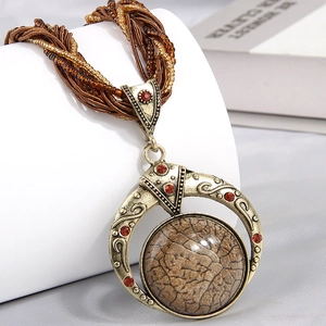 Macro view of vintage gold hollow pendant with brown gemstone and red rhinestones
