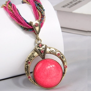 Detail of bohemian pendant with pink marble stone and woven silk cord on a display