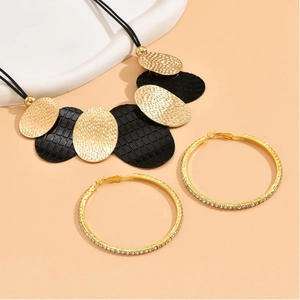 Close-up of bohemian necklace with gold oval pendants and sparkling rhinestone hoop earrings
