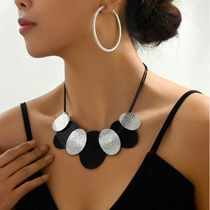 Detail of silver hammered texture and black faux leather on statement necklace and earrings