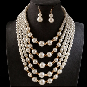 Elegante meerlagige parelketting en oorbellen set met gouden accenten op zwarte display