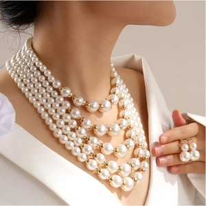 Detail van de vijflaagse parelketting en bijpassende oorbellen op een vrouwelijk model