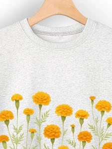 Dettaglio della stampa floreale con calendula gialla su una felpa girocollo grigia