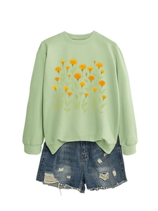 Dettaglio della stampa calendula su felpa verde chiaro con pantaloncini di jeans strappati