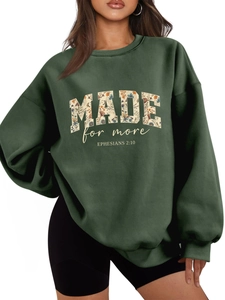 Detail of oversized dark green sweatshirt featuring floral 'MADE' print and Ephesians 2:10 text