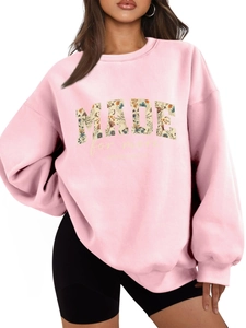 Close-up of pink sweatshirt featuring floral filled MADE letters and bible verse print