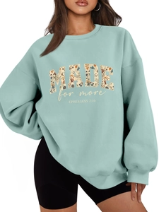 Close-up of mint green crewneck sweatshirt featuring floral MADE for more graphic print