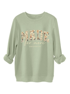 Close-up of sage green sweatshirt featuring floral print MADE FOR MORE lettering and scripture