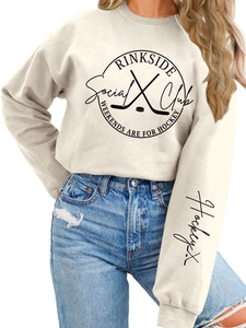 Detail of Rinkside Social Club logo on a thick beige oversized crewneck sweatshirt