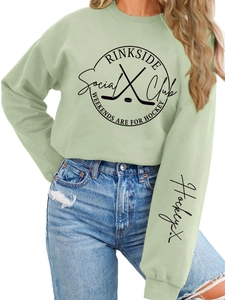 Detail of sage green hockey sweatshirt showing RINKSIDE Social logo and sleeve embroidery