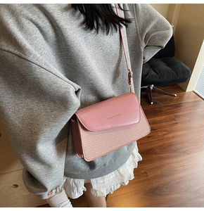 Detail of pink crossbody bag with textured weave and golden FASHION & BAGS logo