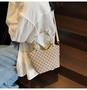 Sac seau vintage avec motif monogramme et anses en cuir porté par un mannequin