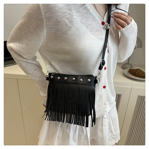 Dettaglio borsa a tracolla nera con frange e borchie indossata con un outfit bianco