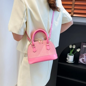 Pink shell handbag with textured fabric and leather straps shown on a model side-view