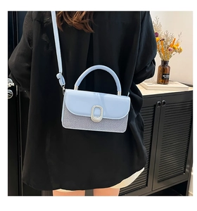 Detail of light blue crossbody bag featuring mixed textures and silver buckle closure