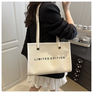 Detail of off-white canvas tote bag featuring LIMITED EDITION print and zipper closure