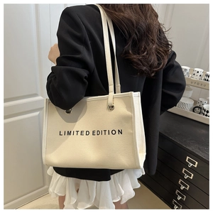 Detail of minimalist off-white canvas tote bag with LIMITED EDITION print worn on shoulder