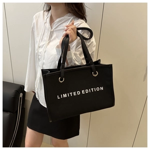 Detail view of large black canvas tote bag featuring white Limited Edition text and metal rings