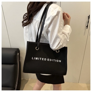 Detail of a black large capacity tote bag with white Limited Edition text and reinforced straps