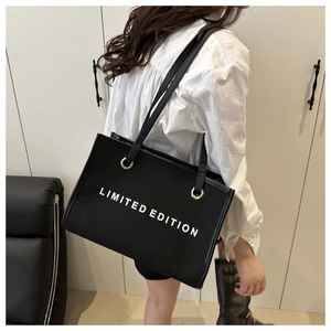 Detailed view of the black canvas tote bag with LIMITED EDITION print worn on shoulder