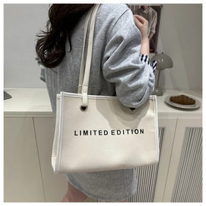 Detailed side view of large canvas tote bag with LIMITED EDITION print worn by a model