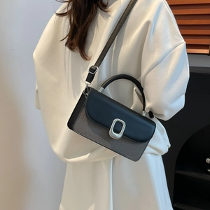 Retro grey and black crossbody bag with silver buckle worn by model in white clothing