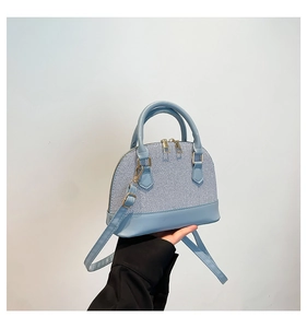 Detail of light blue shell bag featuring woven texture and smooth leather finish