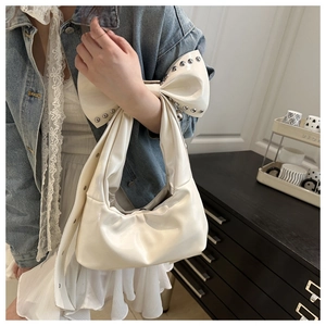Detail of white PU leather bag featuring large bow handle and silver rivet embellishments