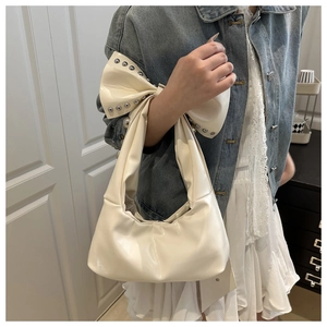 Detail of cream shoulder bag with large bow and silver studs on a stylish strap