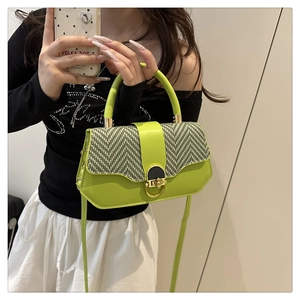 Detail of lime green crossbody bag with black and white herringbone flap and gold ring lock