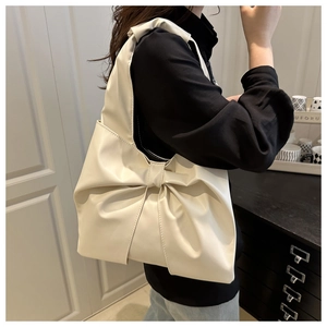 Detailed view of cream-colored oversized bow tote bag in soft matte synthetic leather