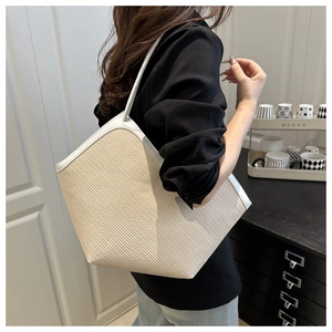 Detailed view of the woven texture and white leather handles on this summer tote bag