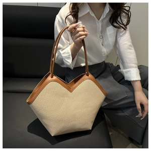 Detail of hand-woven straw tote bag with brown leather trim and slim shoulder straps