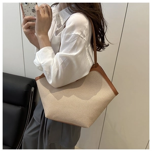 Detail of hand-woven straw tote bag with brown leather handles for summer travel