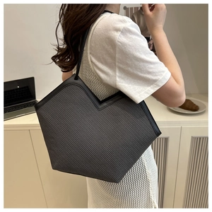 Detail of woven tote bag with unique V-shaped opening and slender black leather straps