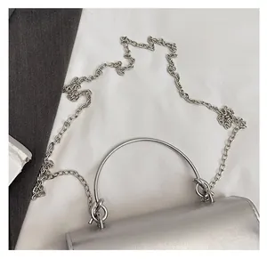 Détail d'un mini sac à main argenté avec une poignée circulaire en métal et une chaîne
