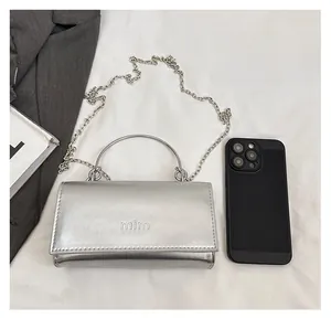 Sac à bandoulière argenté avec chaîne montré à côté d'un smartphone pour la taille