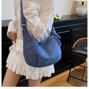 Close-up of blue nylon crescent bag with adjustable wide strap and knotted zipper detail