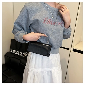 Détail du mini sac en cuir noir avec poignée argentée et bandoulière chaîne