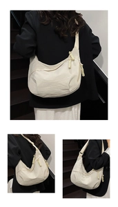 Detail view of large off-white crescent bag with thick rope woven zipper pull detail