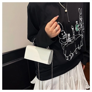 Nahaufnahme der weißen glänzenden Lackleder-Tasche mit Silberkette und Mim-Logo-Prägung