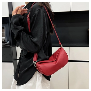Detailed view of red pebble leather crossbody bag with adjustable gold-tone buckle strap