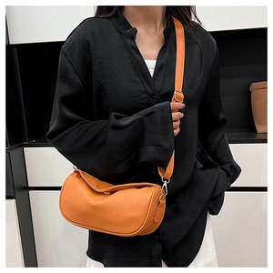 Detail of orange pebble leather crossbody bag with adjustable strap on model