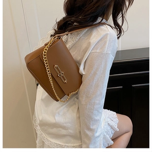 Detail of caramel leather handbag featuring a vintage gold lock and chunky chain strap
