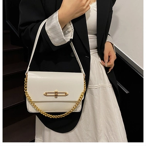 Detail of white leather shoulder bag featuring a gold twist lock and chunky chain strap