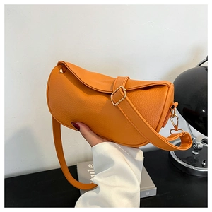 Detail of orange lychee textured leather crossbody bag with elegant gold hardware