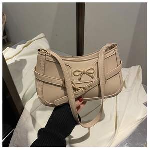 Detail of beige shoulder bag with golden butterfly buckle and decorative side straps
